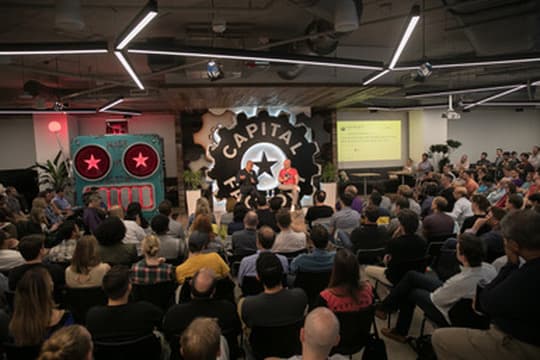 Demo-day audience and the robot mascot on the main stage